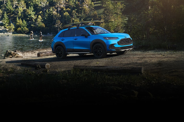 2027 Honda HR-V Sport in Boost Blue Pearl profile parked near a lake with paddleboarders (Subcompact Crossover SUV).